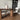 Dining room with wooden table, white chairs, and a vase on the table.