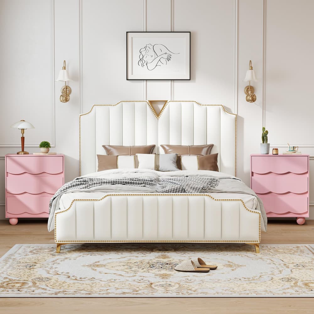 A luxury bedroom setup featuring a white tufted upholstered bed with gold nailhead trim and a matching headboard, flanked by two pink scalloped nightstands with gold lamps, in a styled room with a patterned rug and wall sconces.