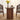 Round wooden side table with a vase of yellow flowers and a cup in a living room setting.