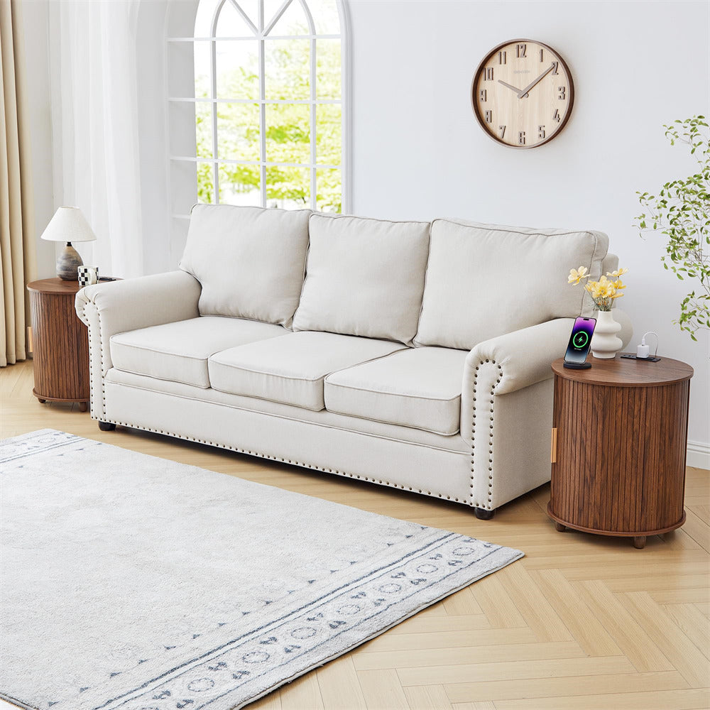 White sofa in a living room with wooden side table and clock on the wall.