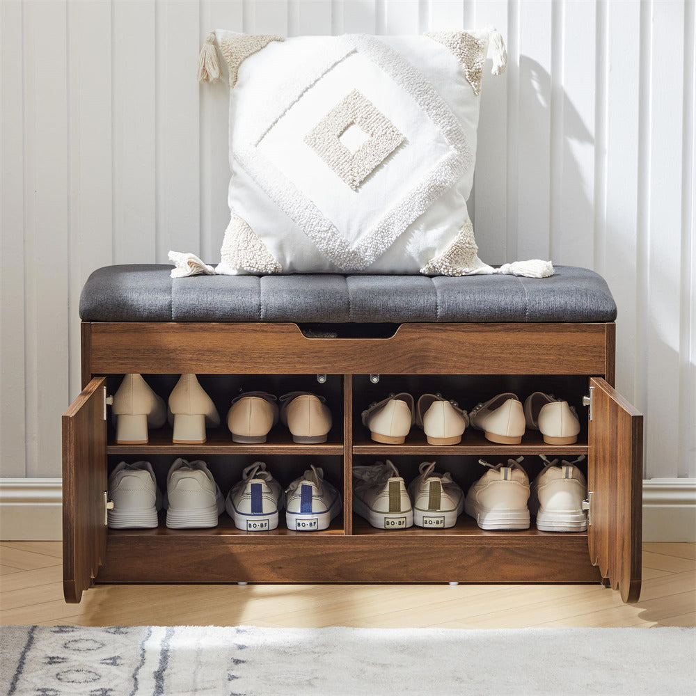 Wooden shoe bench with open storage compartments filled with shoes, cushioned seat, and decorative pillow.