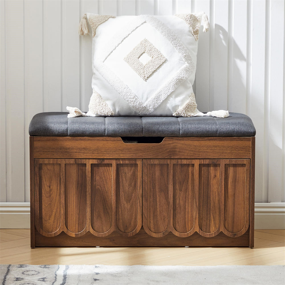 Wooden shoe storage bench with a gray cushion and decorative pillow against a white paneled wall.