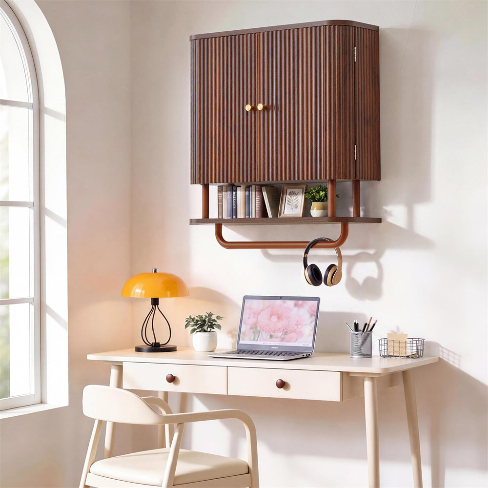 A modern wall-mounted wooden storage cabinet with vertical slats and brass knobs, styled above a light wood desk in a bright home office setting.