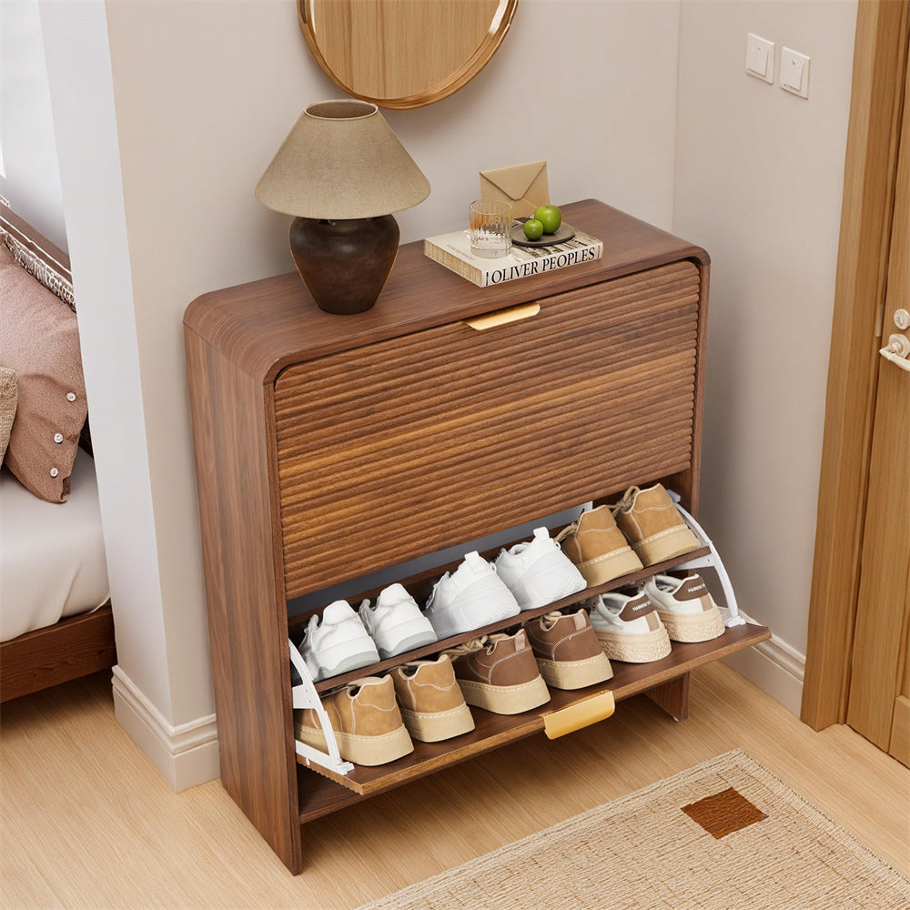 Wooden shoe cabinet with shoes inside, placed next to a bed in a bedroom.