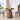 Wooden dining table with chairs in a bright room with large windows.