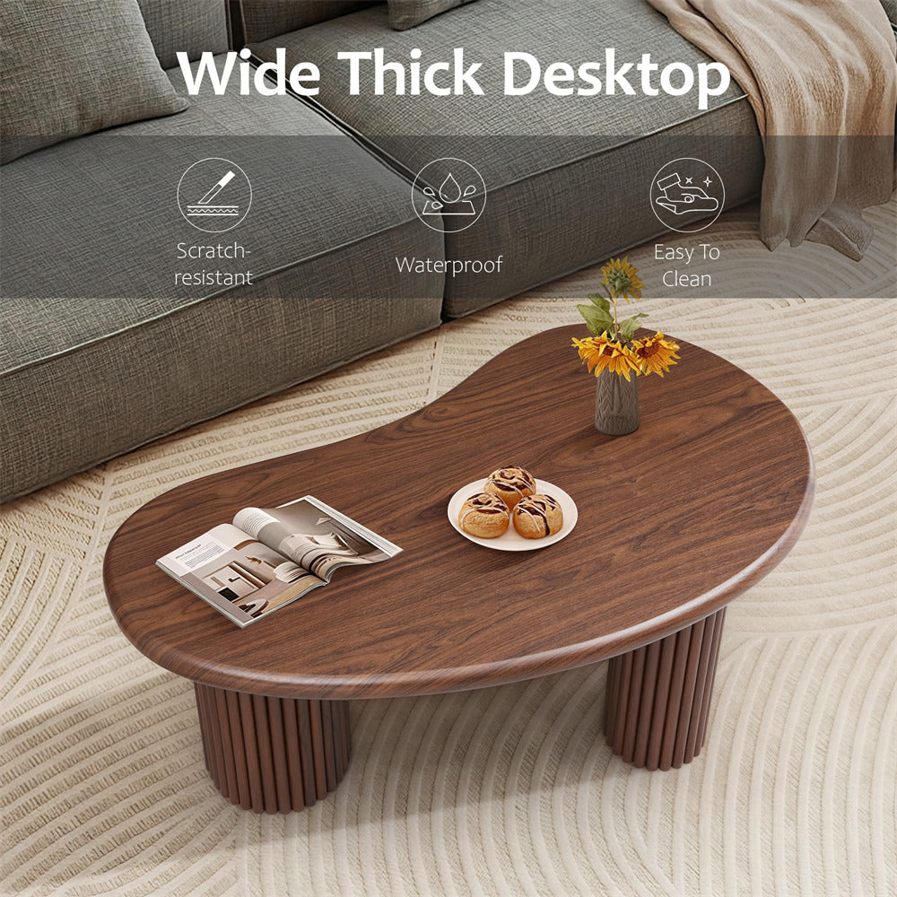 Wooden coffee table with a magazine, plate of cookies, and vase of flowers in a living room setting.