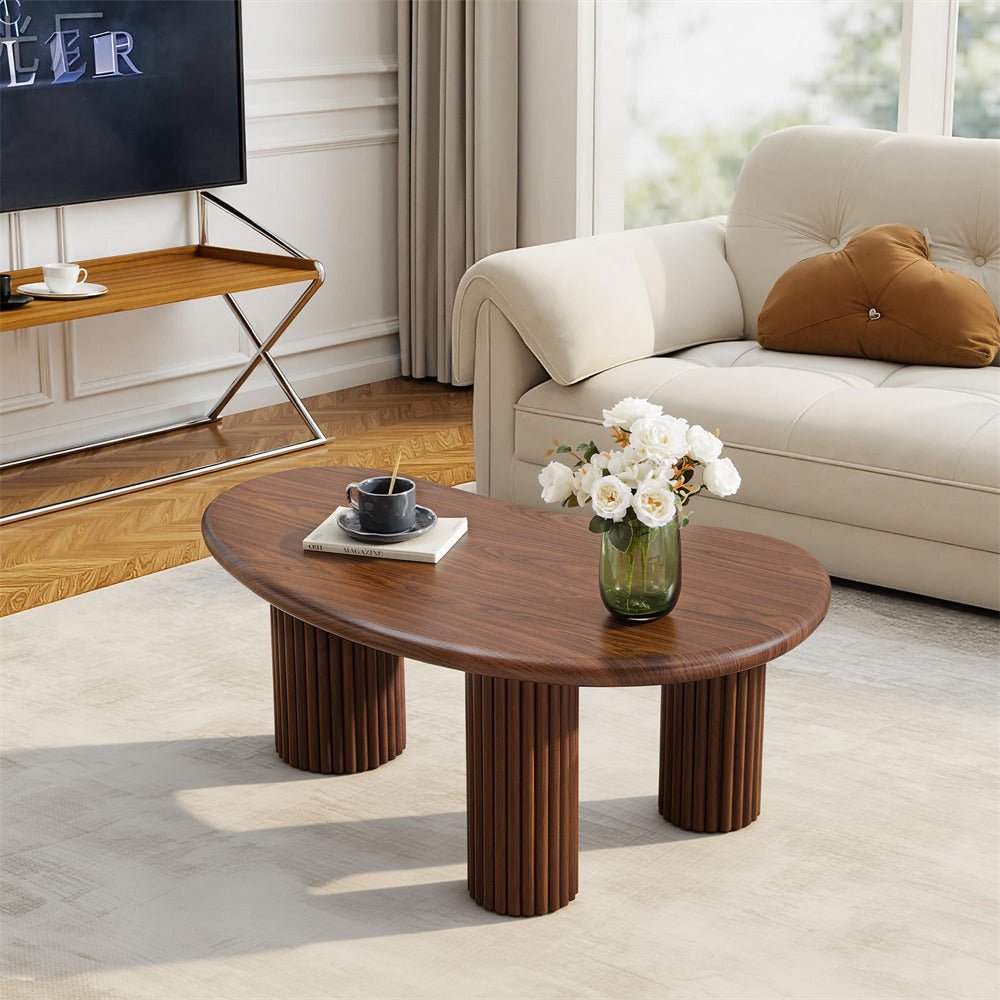 Wooden coffee table in a living room with a vase of flowers and a cup.