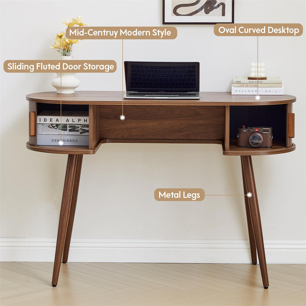 Wooden desk with oval curved desktop, sliding fluted door storage, and metal legs on a light background.