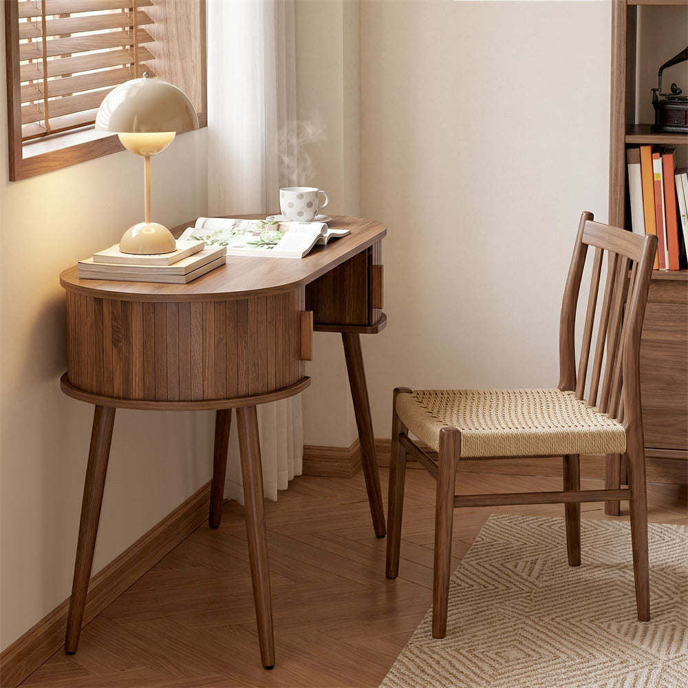 Wooden desk with chair in a room with a lamp and books.