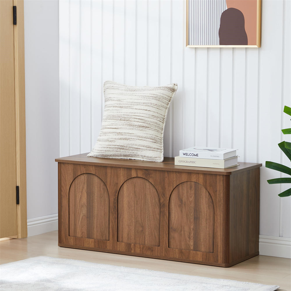Wooden bench with a pillow and books in a room with a white wall and plant.