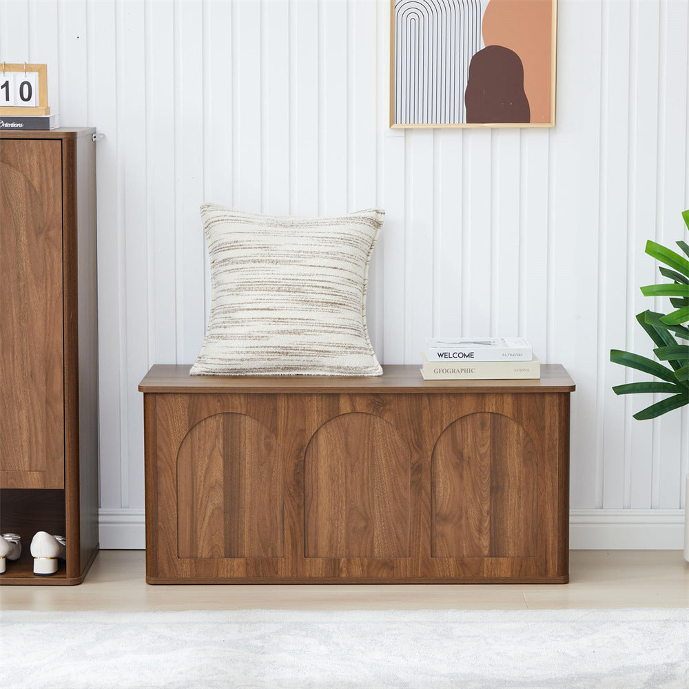 Wooden bench with a pillow and books in a room with a white wall and plant.