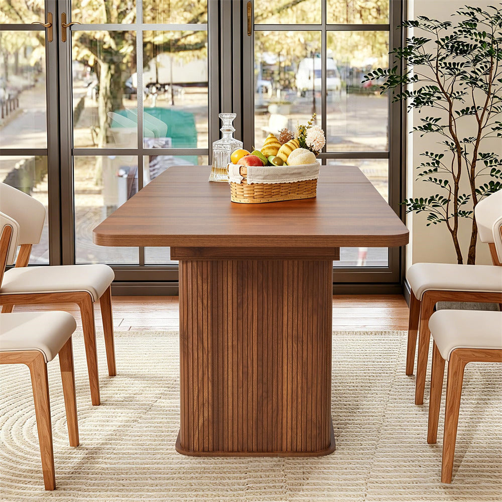 Dining room with wooden table and chairs, fruit basket, and large windows.