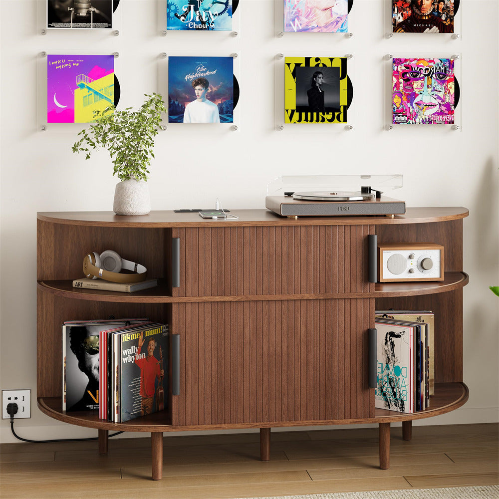 Wooden record player console with vinyl records and a plant against a wall with album covers.