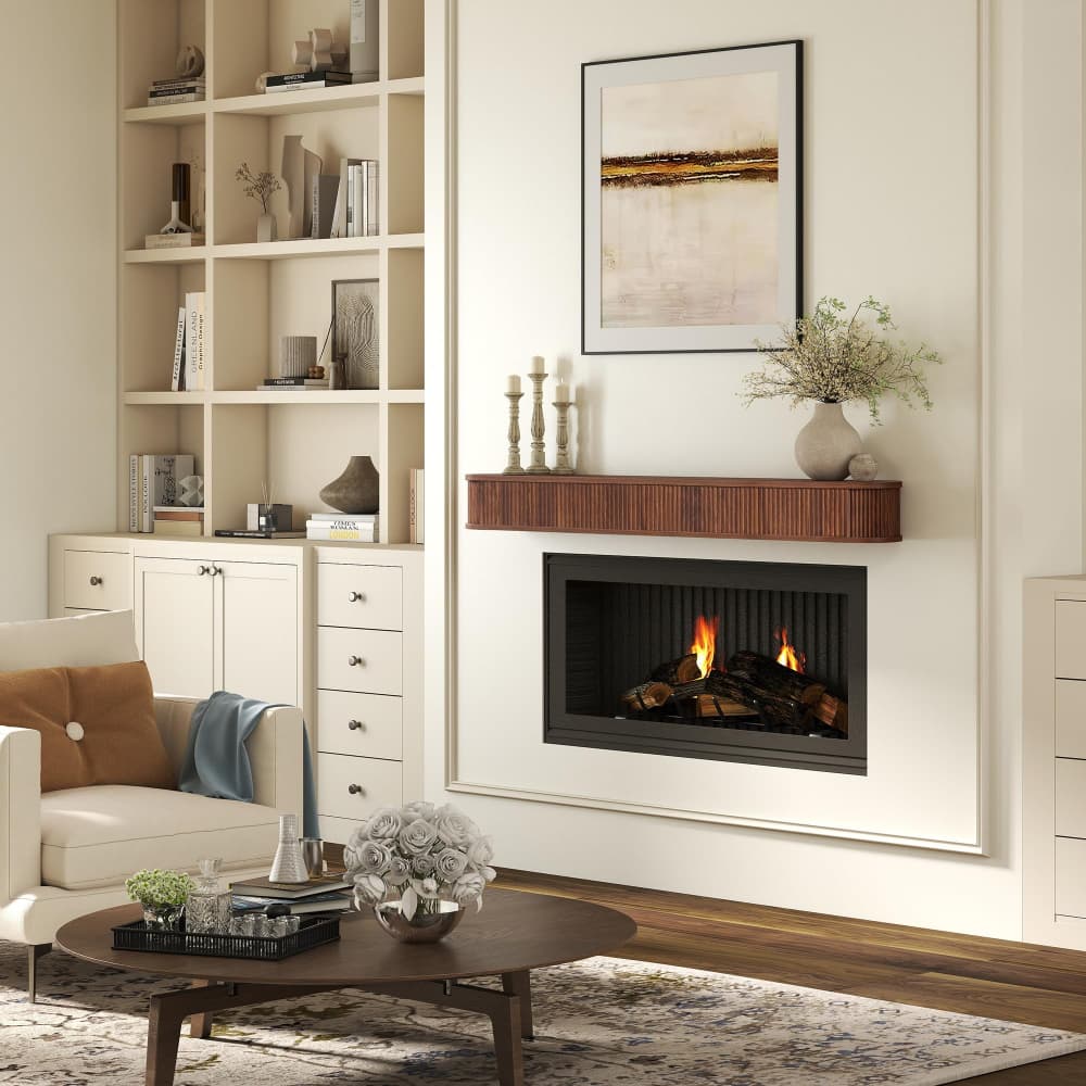 A modern wall-mounted fireplace with a dark wood mantel and black firebox insert, shown in a styled living room with a cream sofa, shelving, and a round coffee table.