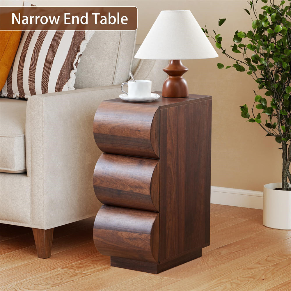 Wooden narrow end table with lamp and cup next to a beige sofa.