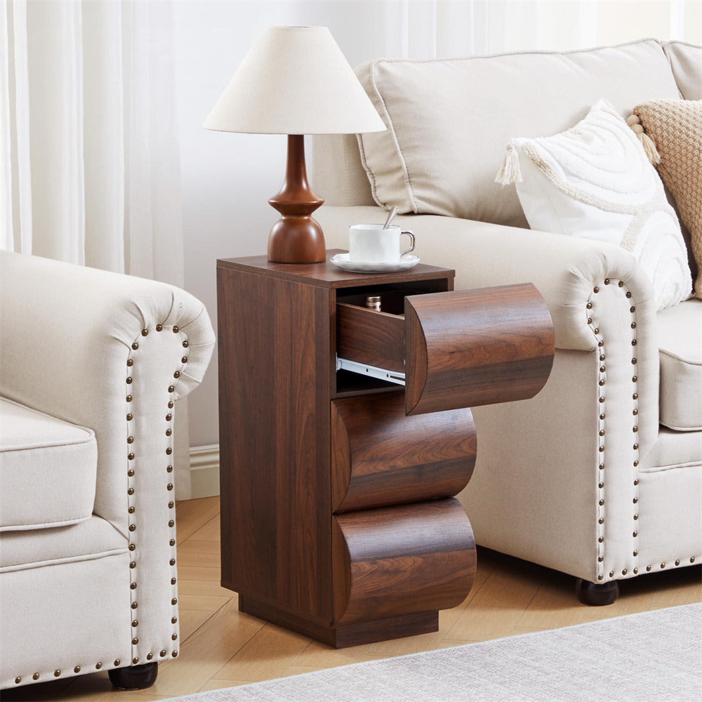 Wooden side table with a drawer next to a beige sofa and armchair in a living room setting.