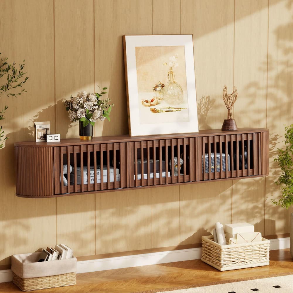 A floating wall-mounted wooden console shelf with vertical slats, styled in a warm, sunlit room with wood-paneled walls, a framed print, flowers, and woven baskets.