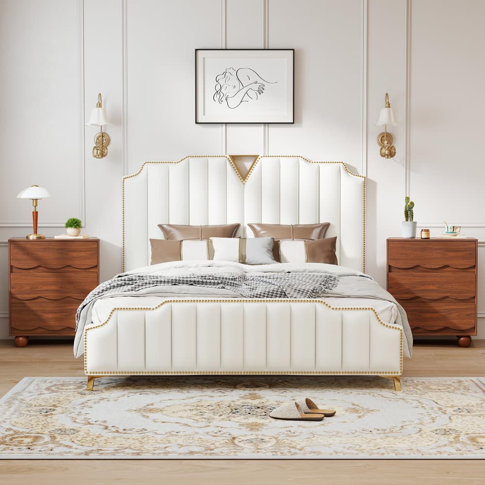 A luxury upholstered bed with a tall channel-tufted headboard and gold nailhead trim, styled in a symmetrical, elegant bedroom with matching wooden nightstands, wall sconces, and a patterned rug.