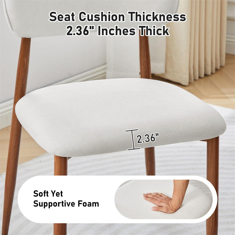 A white upholstered dining chair with wooden legs shown in a room setting, with text indicating a seat cushion thickness of 2.36 inches and a callout of the same color showing a hand pressing into the cushion to demonstrate soft yet supportive foam.