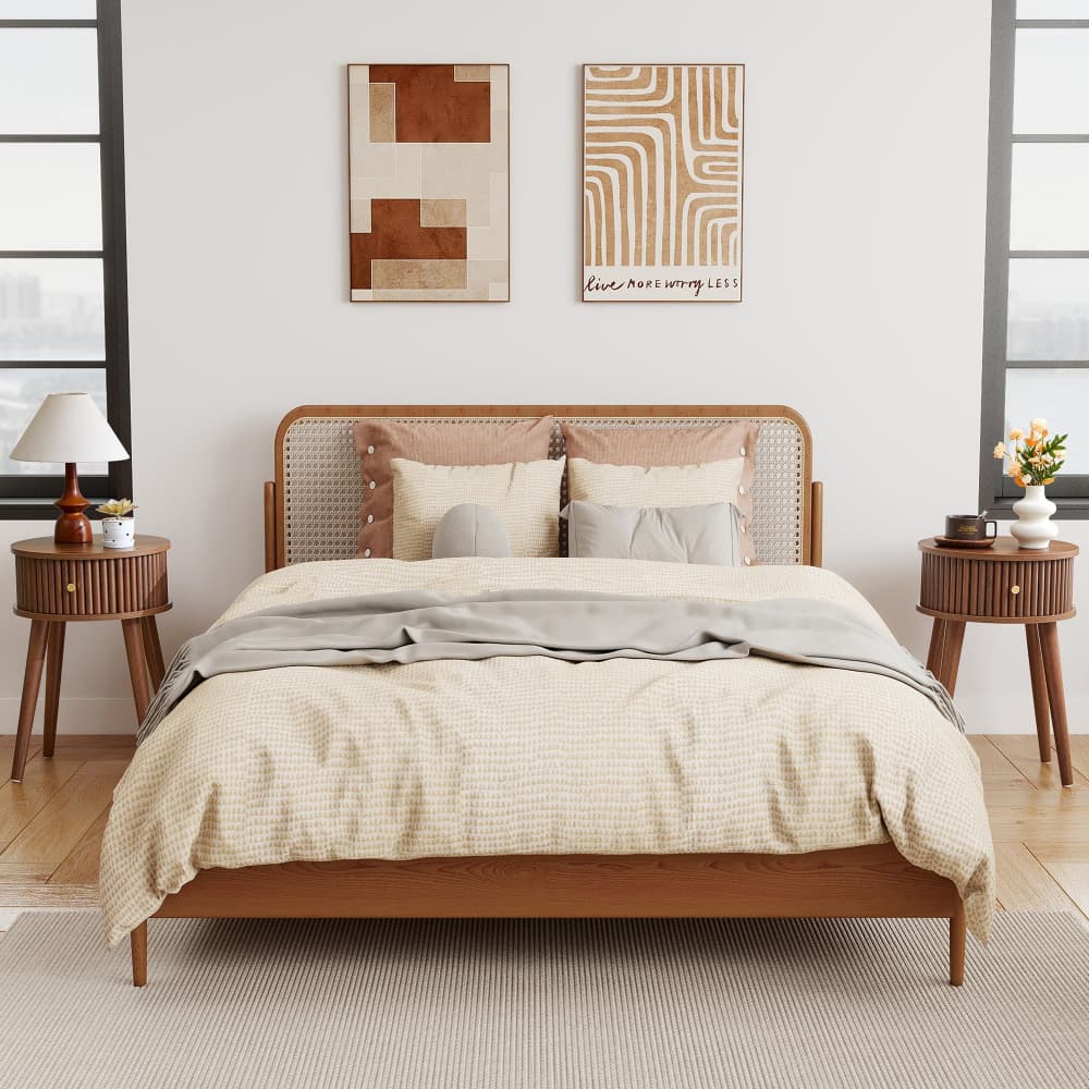 A wooden bed frame with a woven cane headboard, styled with beige and gray bedding, flanked by matching wooden nightstands in a bright, modern bedroom.