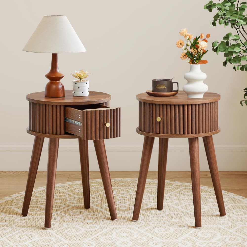 Two mid-century modern wooden end tables with ribbed cylindrical sides and tapered legs, styled in a warm room setting. One table is open, showing a drawer with a brass pull handle, while the other is closed.