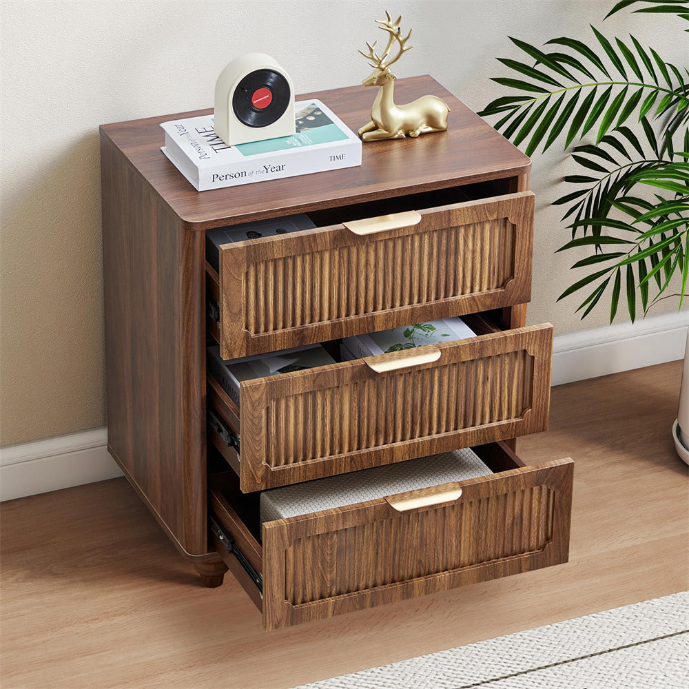 Wooden nightstand with three drawers, decorative items, and a plant in the background.
