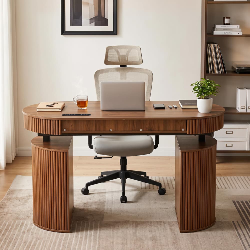 A modern curved wooden desk with fluted legs and a matching office chair, styled in a bright home office setting with a laptop, plant, and books.