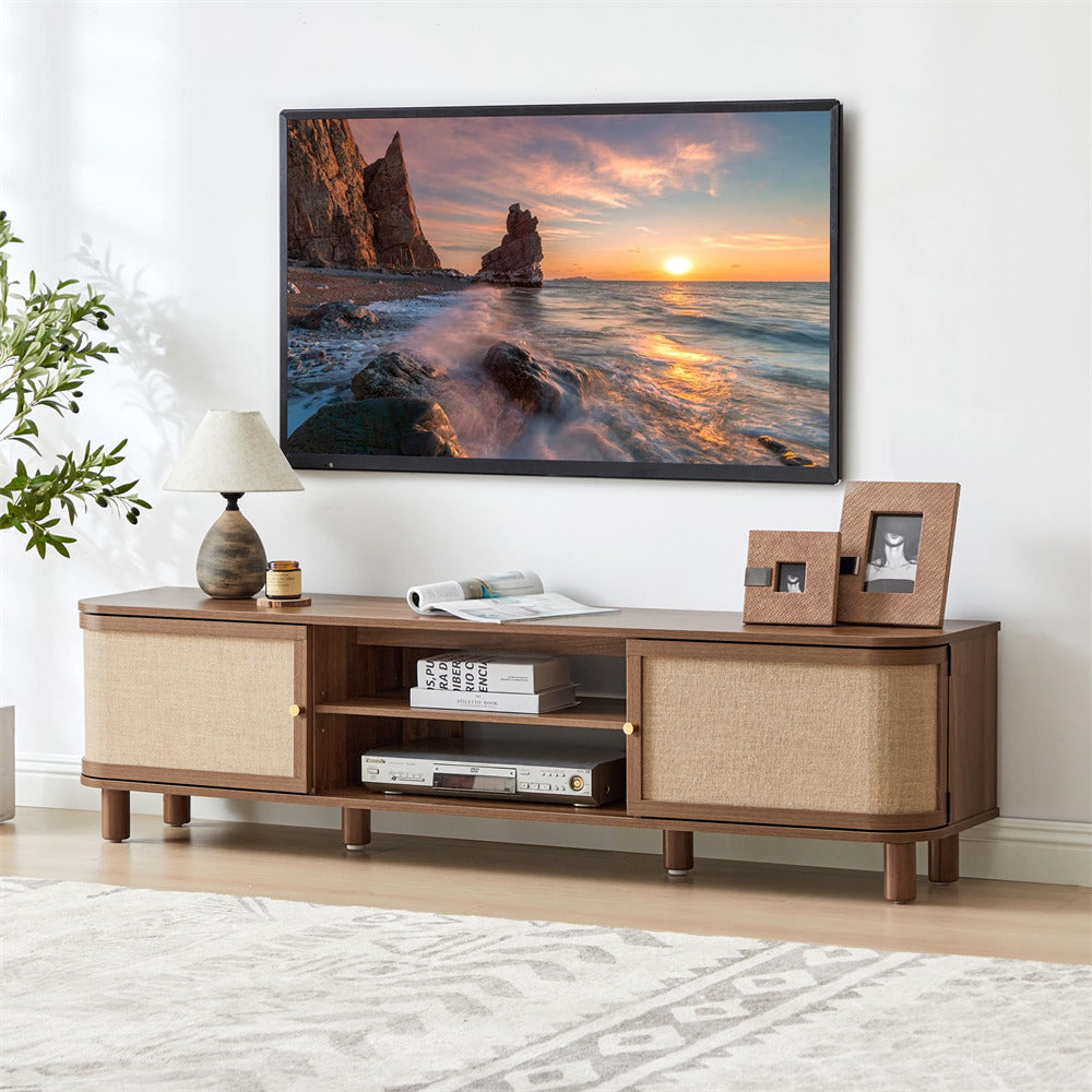 Wooden TV stand with a television displaying a sunset over water scene, in a room with a lamp and decorative items.