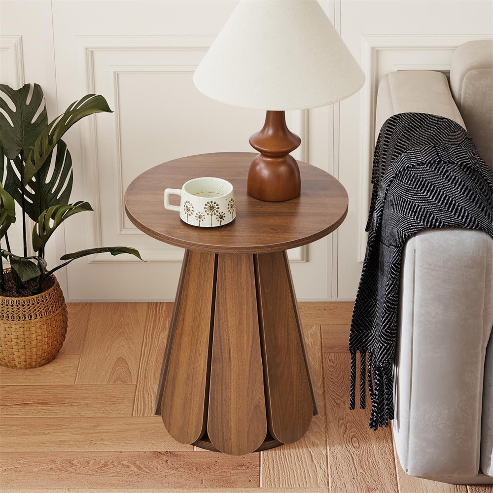 Wooden side table with a lamp and mug next to a sofa in a living room.