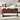 Wooden coffee table with a laptop and cup in front of a beige sofa with patterned cushions.