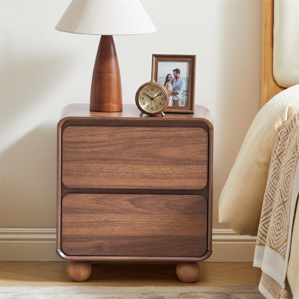 Wooden nightstand with lamp, clock, and photo frame on a bedroom sideboard.
