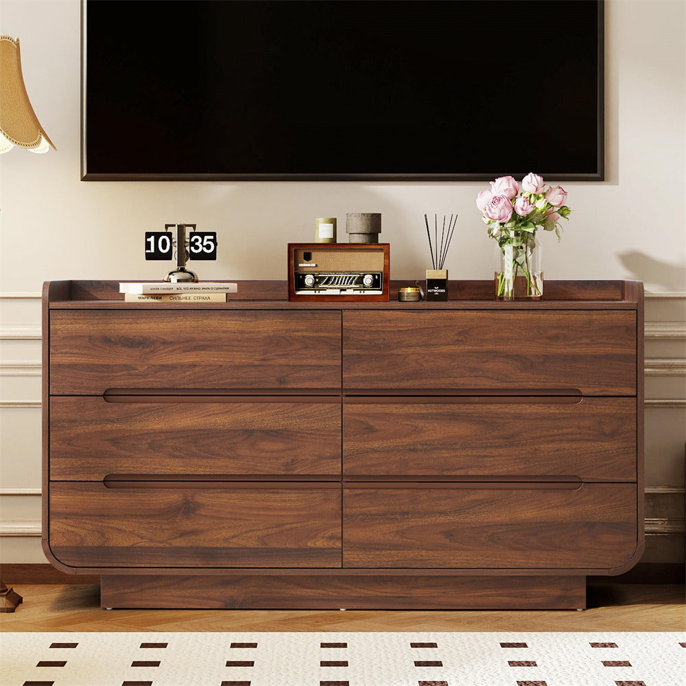 Wooden dresser with decorative items against a wall with a television.