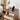 Wooden nightstand with a smartphone on a stand, books, and a vase with flowers.