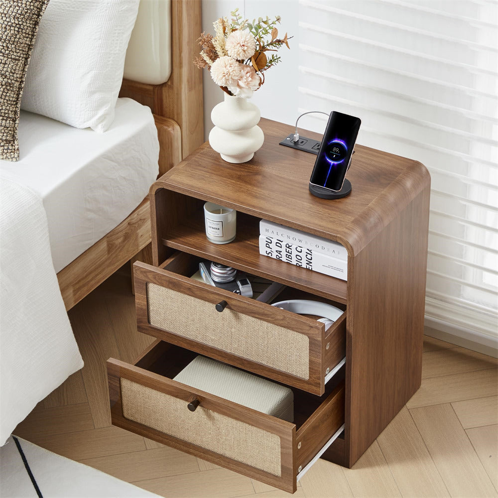 Wooden nightstand with drawers, phone, and decor items next to a bed.