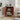 Wooden corner shelf with decorative items in a room with a plant and window.