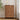 Wooden 5 drawer dresser with decorative items against a neutral wall