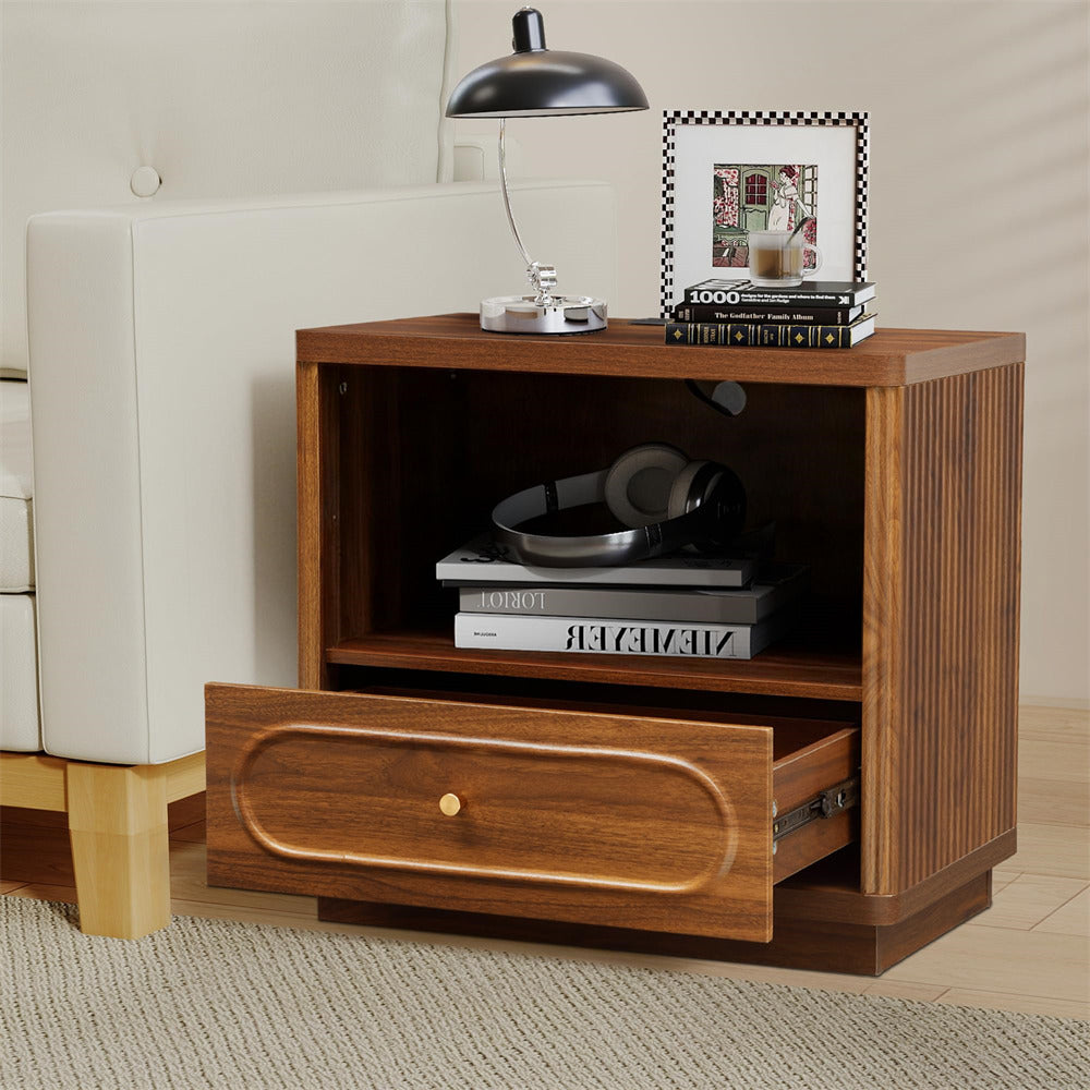 Wooden nightstand with open drawer, books, and a lamp in a living room setting.