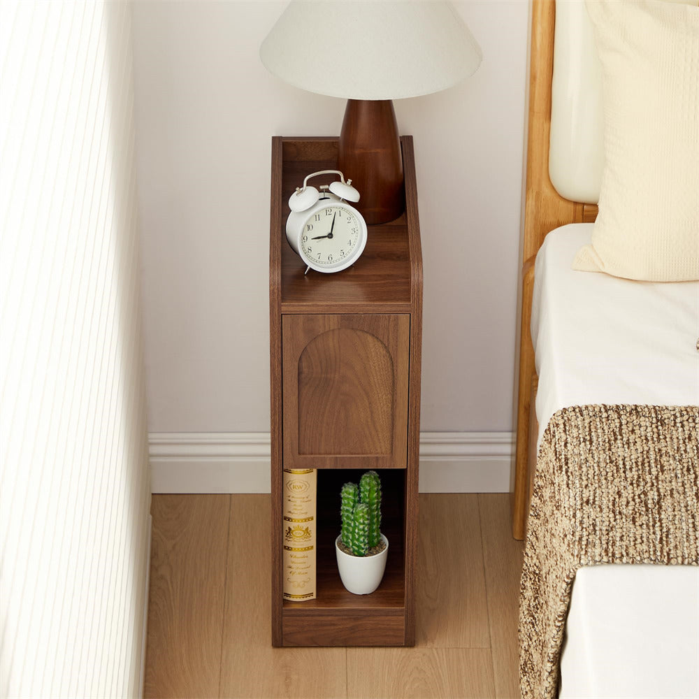 Wooden nightstand with clock, books, and plant next to a bed