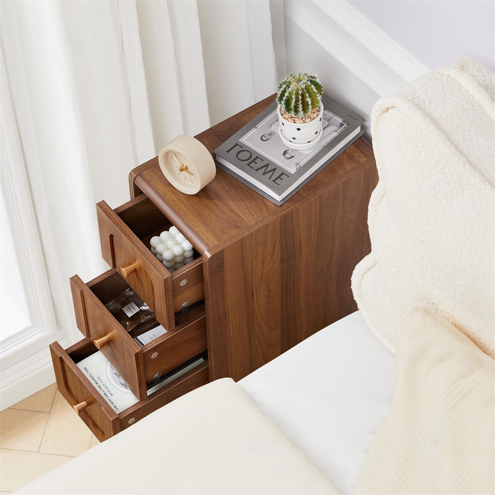 Wooden nightstand with open drawer next to a bed in a bedroom setting