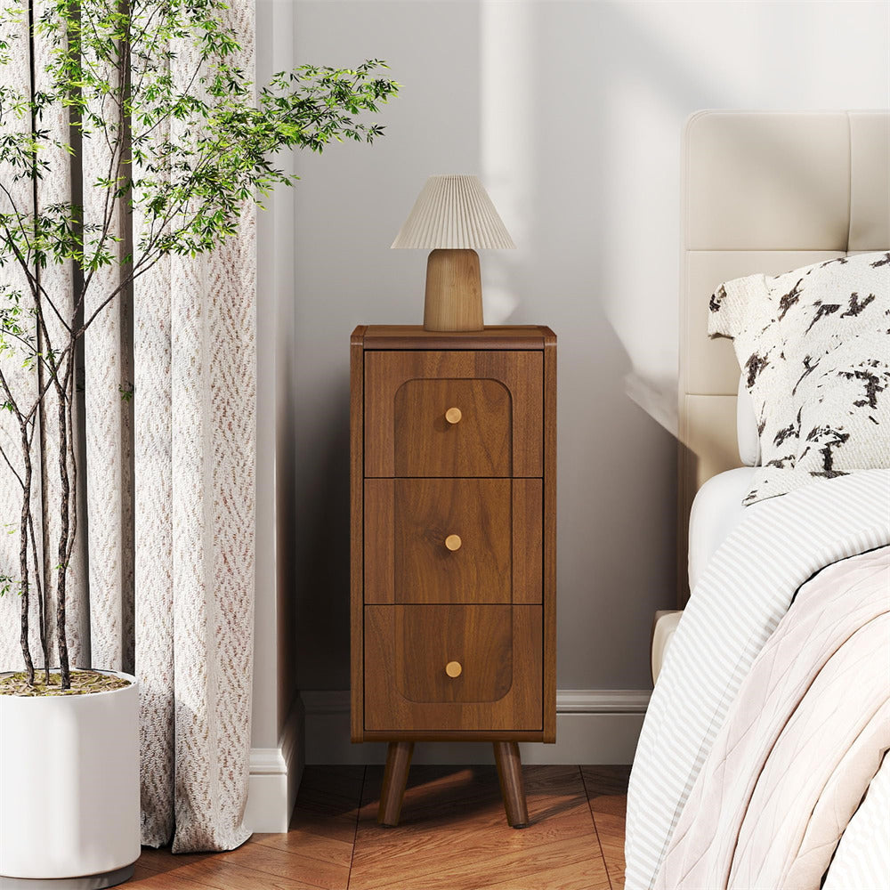 Wooden nightstand with lamp next to a bed in a bedroom setting