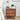 Wooden walnut nightstand with floral carvings, lamp, and books in a bedroom setting.