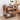 Wooden side table with decorative carvings, books, and a vase on a light wood floor.