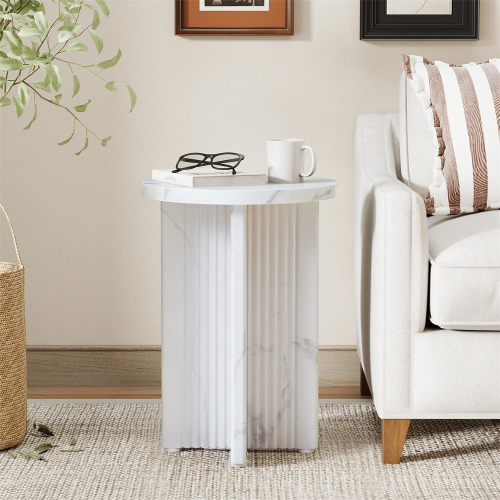 Small side table with marble top and fluted columns next to a white armchair with striped pillow.