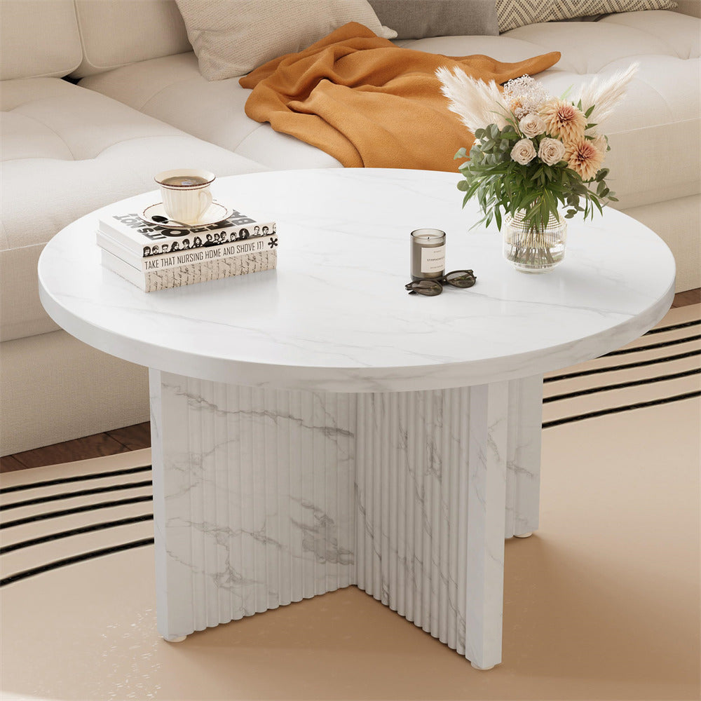 Round marble coffee table with decorative items in a living room setting