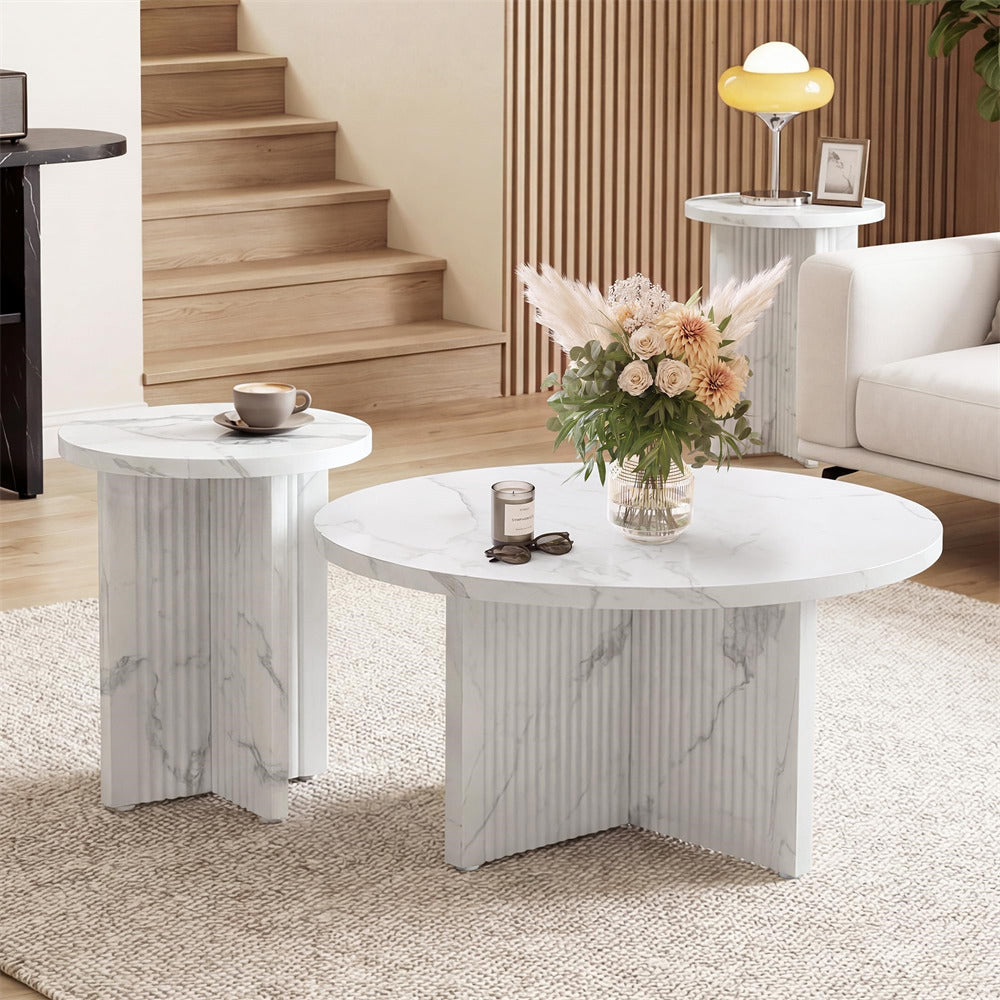 Round marble coffee table with a vase of flowers and a cup on a rug in a living room.