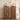 Two matching narrow wooden side tables or cabinet stands with arched drawer fronts and round brass knobs, shown in a styled interior scene with a clock, mug, lamp, framed print, and plant shadows on the wall.