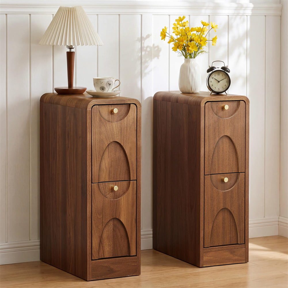 Two matching mid-century modern wooden nightstands with arched drawer fronts and small gold knobs, styled with a lamp, cup, flowers, and an alarm clock against a white paneled wall.