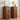 Two matching mid-century modern wooden nightstands with arched drawer fronts and small gold knobs, styled with a lamp, cup, flowers, and an alarm clock against a white paneled wall.